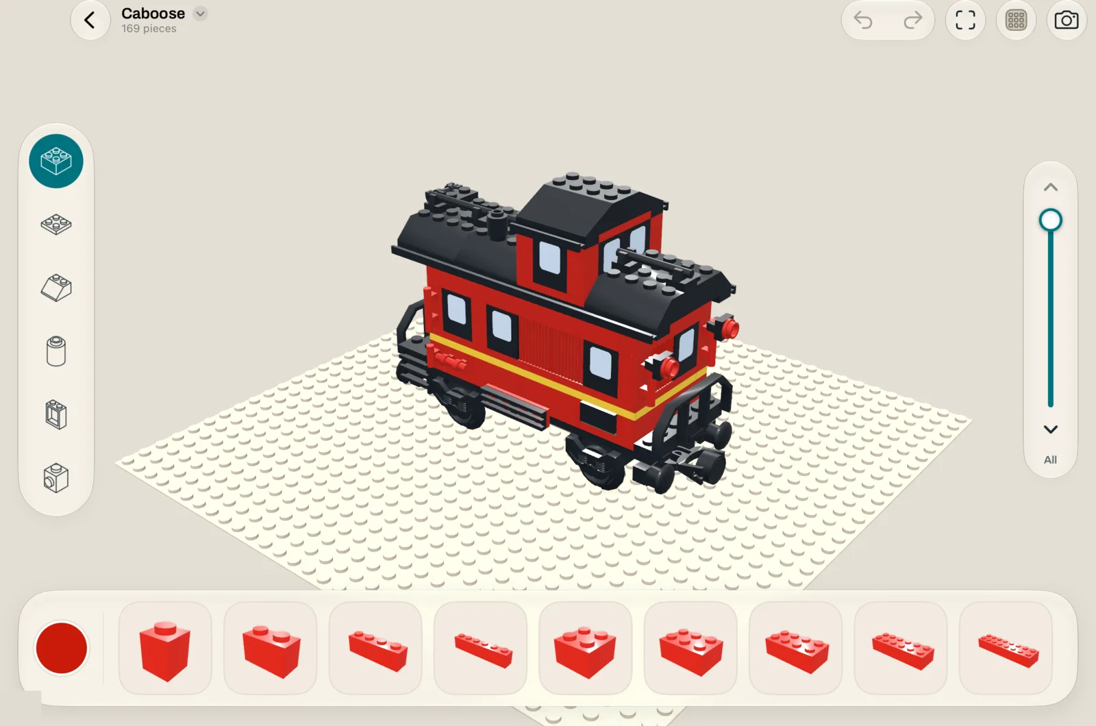 The Klodstudio editor on iPad with a red train caboose model on a baseplate, the piece tray along the bottom and the category rail on the left.